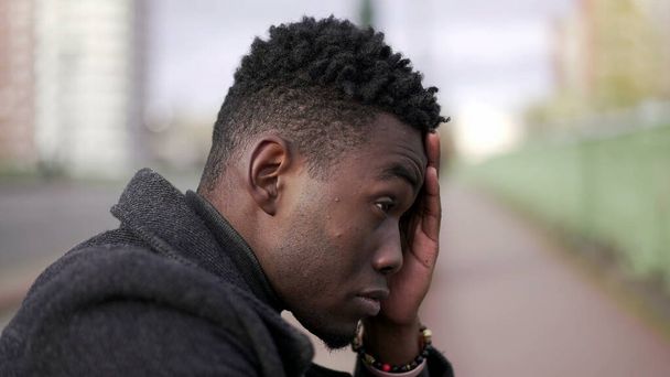 Anxious young black man suffering emotional pain sitting on sidewalk in street - Valokuva, kuva