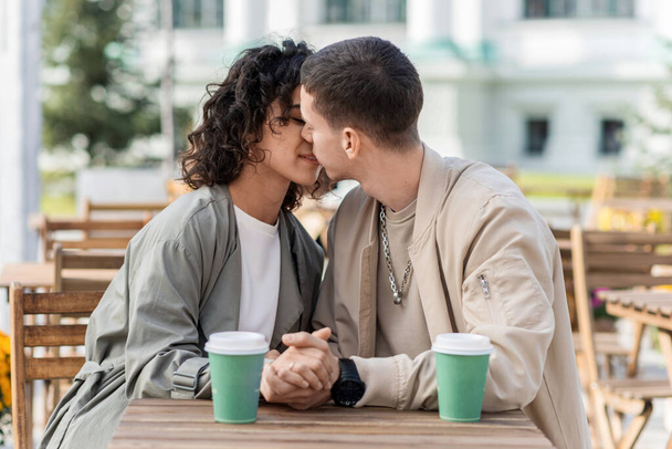 Una coppia romantica all'aperto vicino a un bar. Mani in alto, baci, caffe 'sul tavolo. Atmosfera d'autunno - Foto, immagini