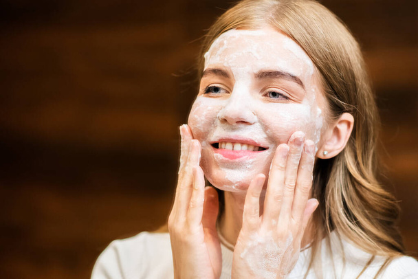 A young caucasian smiling woman is making a face mask - Photo, Image