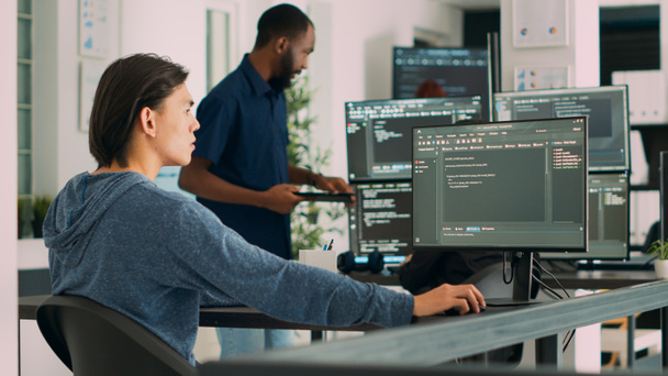 Programista wpisując kod aplikacji uczenia się na komputerze, siedzi przy biurku w biurze big data. Programista chmury pracujący ze skryptem bazy danych html w agencji bezpieczeństwa cybernetycznego. Strzał ręczny. - Zdjęcie, obraz