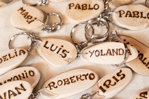 voorgrond van handgemaakte houten sleutelhangers gegraveerd met de juiste Spaanse namen. selectieve focus - Foto, afbeelding