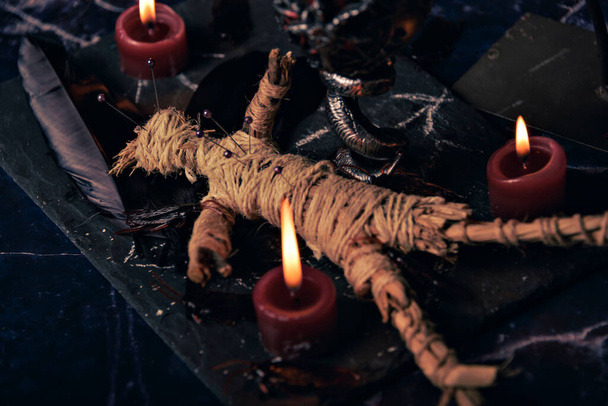 Voodoo-Puppe in ritueller Nahaufnahme, magischer Tisch mit Kerzen, Hexerei und Spiritualitätskonzept - Foto, Bild