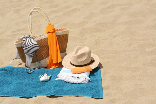 Blue towel, bag and accessories on sandy beach, space for text - Фото, изображение