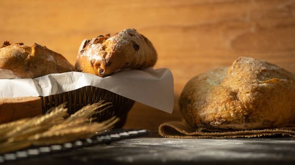 素朴な木製のテーブルの上に自家製のソース生地のパンと小麦. - 写真・画像