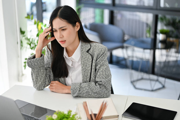 Gestresste jonge Aziatische zakenvrouw of vrouwelijke manager controleren van haar werk op laptop scherm, pensive denken en het plannen van nieuwe strategie. - Foto, afbeelding