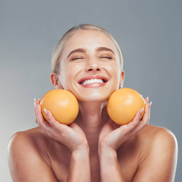 Orange, skincare and woman in studio with fruit for a natural beauty facial cosmetics product with mockup space. Smile, vitamin c and happy young girl detoxing her glowing face organically to relax. - Photo, Image