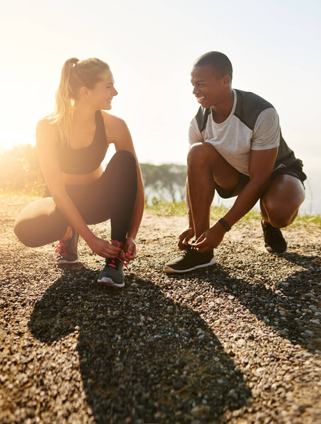 Are you ready. a fit young couple tying their shoelaces before a run outdoors - Photo, Image