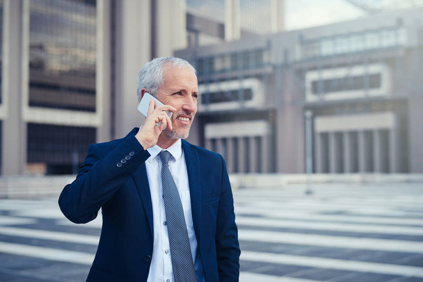 Es un hombre de negocios en movimiento. un hombre de negocios que contesta su teléfono mientras camina a su oficina en la ciudad - Foto, imagen