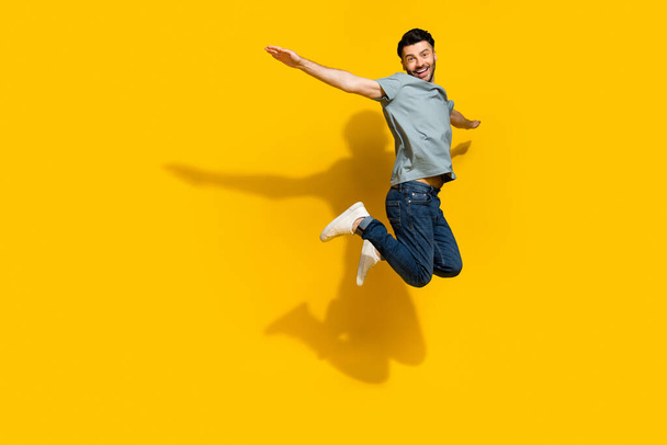 Foto de perfil de tamaño completo de la persona satisfecha alegre saltando alas de los brazos volando aislado sobre fondo de color amarillo. - Foto, imagen