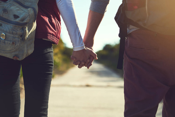 Készen áll a kalandra. Visszapillantás egy fiatal párról, akik kéz a kézben sétálnak a túraúton. - Fotó, kép