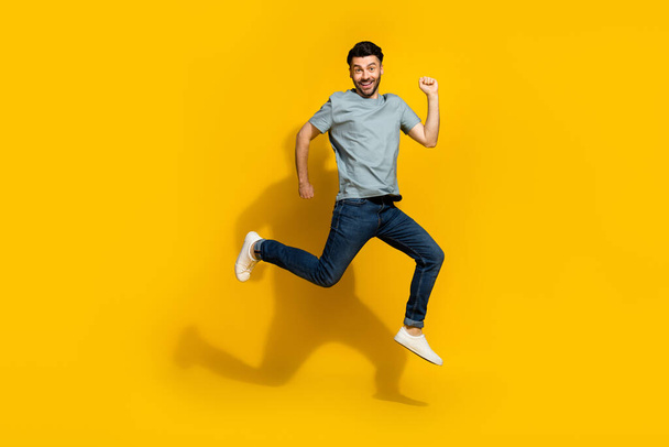 Full size photo of energetic overjoyed person jumping running hurry isolated on yellow color background. - Foto, Imagem