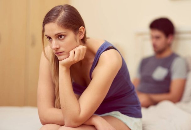 Come rimettiamo in carreggiata questa relazione? una giovane donna infelice seduta sul letto dopo aver litigato con il suo ragazzo - Foto, immagini