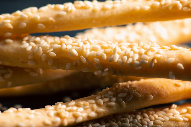 Grissini mit Sesamsamen, auch als Brotstangen, Grissino oder Dip-Sticks bekannt, sind in der Regel bleistiftgroße Stangen aus knusprigem, trocken gebackenem Brot aus Italien.. - Foto, Bild