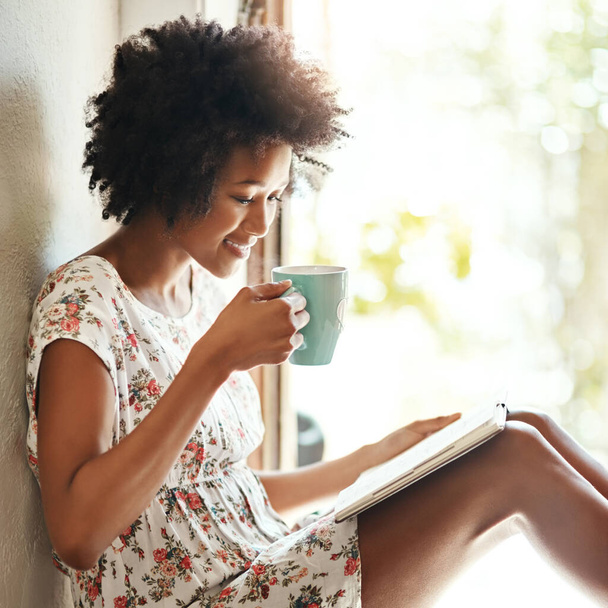 週末を通して読む。家でコーヒーと本を飲みながらリラックスした若い女性が - 写真・画像