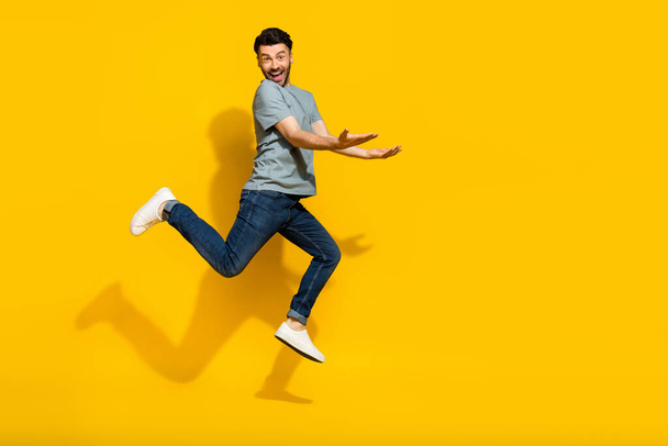 Full length photo of cheerful crazy man hand hold carry empty space dressed stylish clothes isolated on yellow color background. - 写真・画像