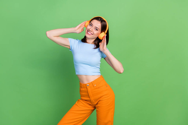 Portrait of lovely satisfied person arms touch headphones beaming smile isolated on green color background. - Zdjęcie, obraz