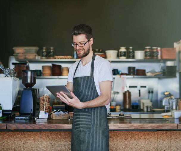 Řídí jeho kavárnu online. mladý barista pomocí tabletu ve své kavárně - Fotografie, Obrázek