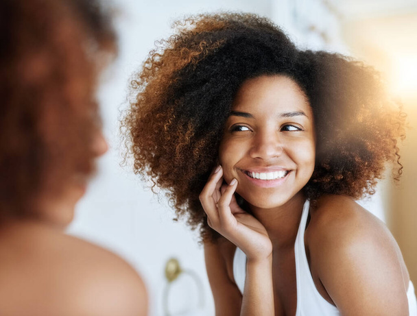Good skincare pays off. an attractive young woman admiring her skin in front of the bathroom mirror - Zdjęcie, obraz