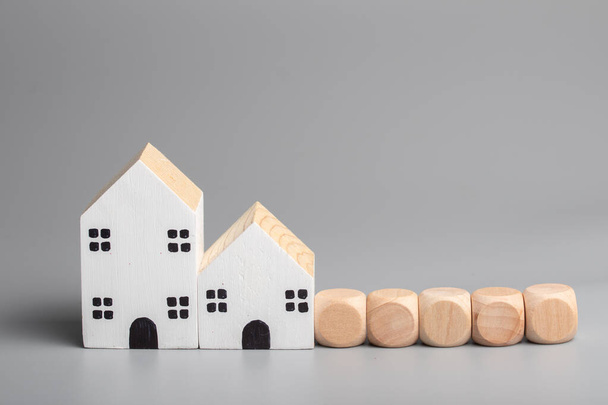 Дерев'яний будинок і дерев'яні кубики на сірому фоні. Концепція фінансування нерухомості
. - Фото, зображення