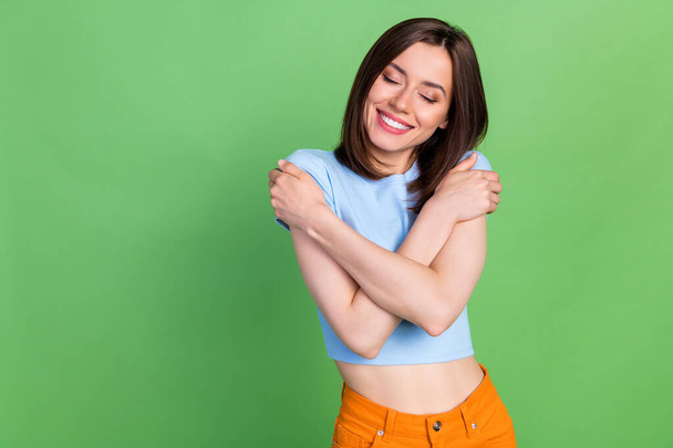 Photo of cheerful nice person closed eyes toothy smile arms hug shoulders isolated on green color background. - Photo, Image