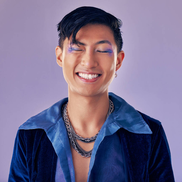 Fashion, color and man in studio for punk, retro and pop art style while feeling happy with makeup and vintage clothes on a purple background. Lgbtq, gen z and asian aesthetic model with makeup. - Foto, Imagen