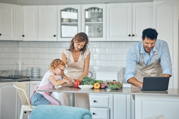 Kitchen, cooking and family with laptop with vegetables, food nutrition information and internet recipe search for healthy, vegan lifestyle. Parents and child learning together for lunch or dinner. - Photo, image