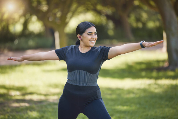 Woman, music earphones and yoga in park, nature environment or sustainability location for wellness, health or body mobility. Smile, happy or stretching yogi listening to zen podcast or mindset radio. - Photo, Image