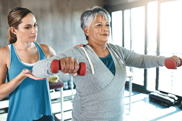 Viver activo, viver bem. uma mulher idosa usando pesos com a ajuda de um fisioterapeuta - Foto, Imagem