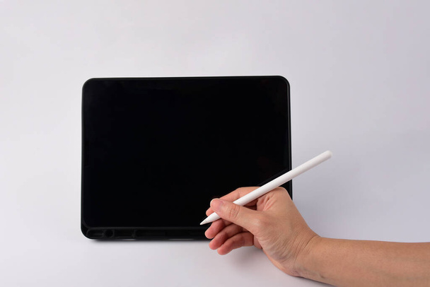 Penna in mano e smartphone e stilo nero per scrivere isolato su sfondo bianco.  - Foto, immagini