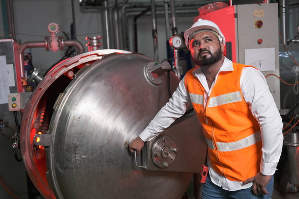 Zuid-Azië mannelijke fabrieksarbeider of Man ingenieur of deskundige medewerkers dragen veiligheidsvest en helm van onderhoud en controle stoomketel - Foto, afbeelding