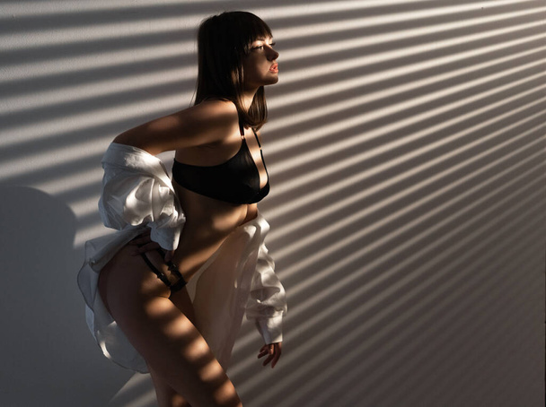 Sexy mooi meisje in zwarte lingerie met schaduw op slanke lichaam. sensuele naakte vrouwen - Foto, afbeelding