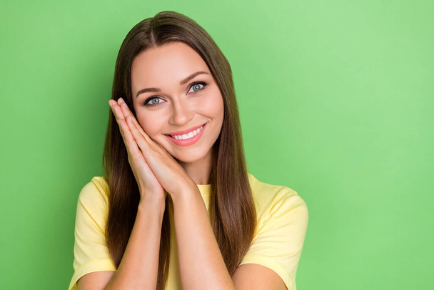 Portrait of funny gorgeous girl with long hairstyle dressed yellow t-shirt hands under cheek pause isolated on green color background. - Photo, Image