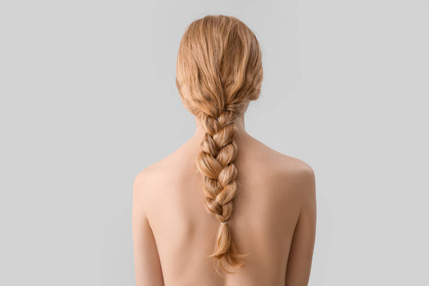Młoda kobieta z warkoczem fryzura na jasnym tle - Zdjęcie, obraz