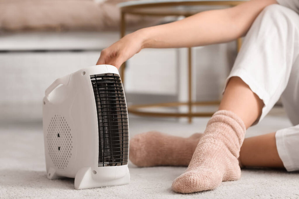 Calentador de ventilador eléctrico moderno y mujer en calcetines calientes en la alfombra, primer plano - Foto, Imagen