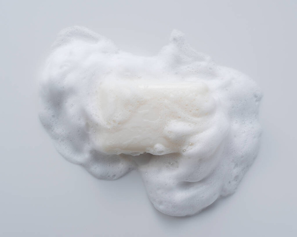 Solid soap with foam placed on white background. Viewed from directly above. - Фото, изображение