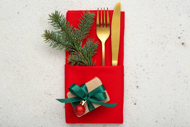 Holder kultainen ruokailuvälineet, kuusen oksa ja joululahja kevyellä taustalla - Valokuva, kuva