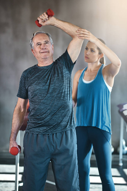 Making the senior years the super years. a senior man using weights with the help of a physical therapist - Photo, Image