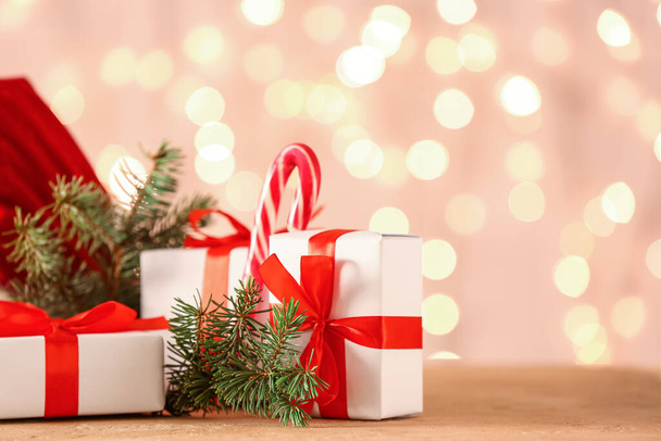Рождественские подарки и елки на столе против размытых огней - Фото, изображение