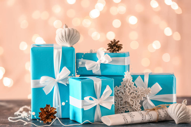 Πολλά δώρα Χριστουγέννων, νότες μουσικής και διακοσμήσεις στο τραπέζι κατά θολή φώτα - Φωτογραφία, εικόνα