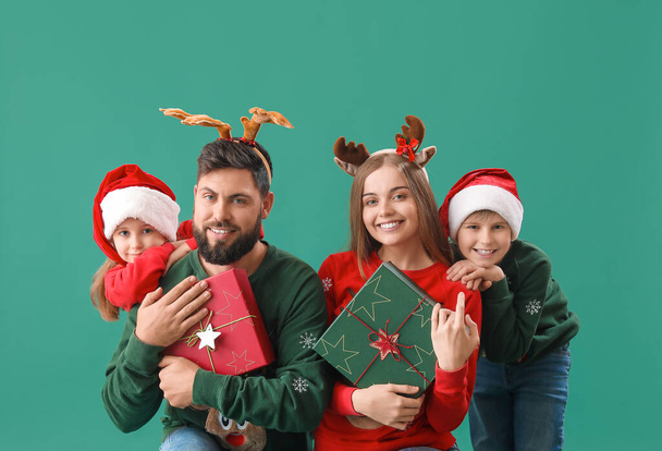 Ευτυχισμένη οικογένεια με δώρα Χριστουγέννων στο πράσινο φόντο - Φωτογραφία, εικόνα
