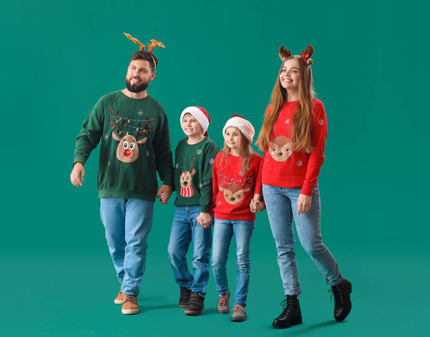 Happy family in Christmas clothes holding hands on green background - Foto, Imagen
