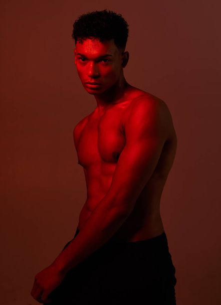Black man, body and dark light on red background in studio for exercise, training or workout bodybuilder, personal trainer or coach. Portrait, fitness model or red light aesthetic for health wellness. - Foto, imagen