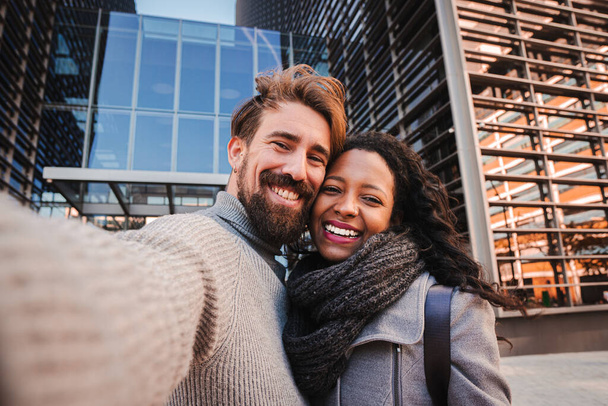 Young man and woman tourist making selfie and smile to the camera. Boyfriend and girlfriend having fun outdoors doing a portrait with smartphone. Travel concept. High quality photo - Photo, Image