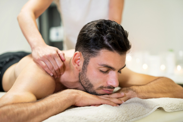 Crop massagem terapeuta amassar ombros de cliente masculino relaxado durante sessão de spa no salão - Foto, Imagem