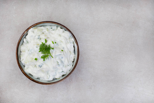 Čerstvě řecké oblíbené, Tzatziki s okurkou, jogurtem a bylinkami. Na skvrnitém šedém povrchu s kopírovacím prostorem - Fotografie, Obrázek