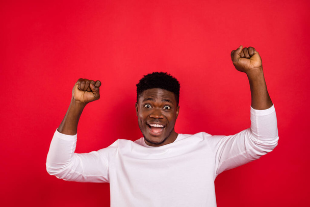 Photo of astonished delighted person raise fists triumph achieve isolated on red color background. - Фото, зображення