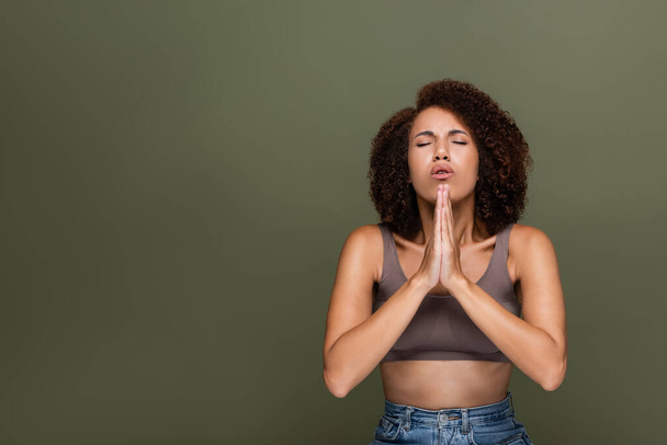 Curly african american woman with closed eyes praying isolated on green  - Foto, Imagem
