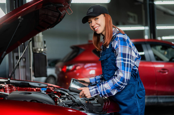 Caucasian female auto mechanic uses a special computer to diagnose faults - Photo, Image