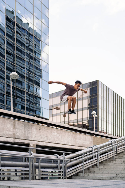 Concentrated cool man practicing parkour tricks in the city and having fun. - Fotoğraf, Görsel