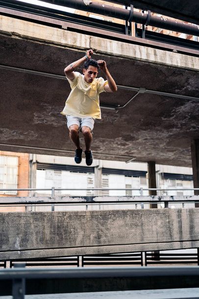 Concentrated cool man practicing parkour tricks in the city and having fun. - Foto, Imagen